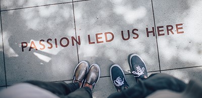 feet standing on tile with the text "passion led us here" written on it